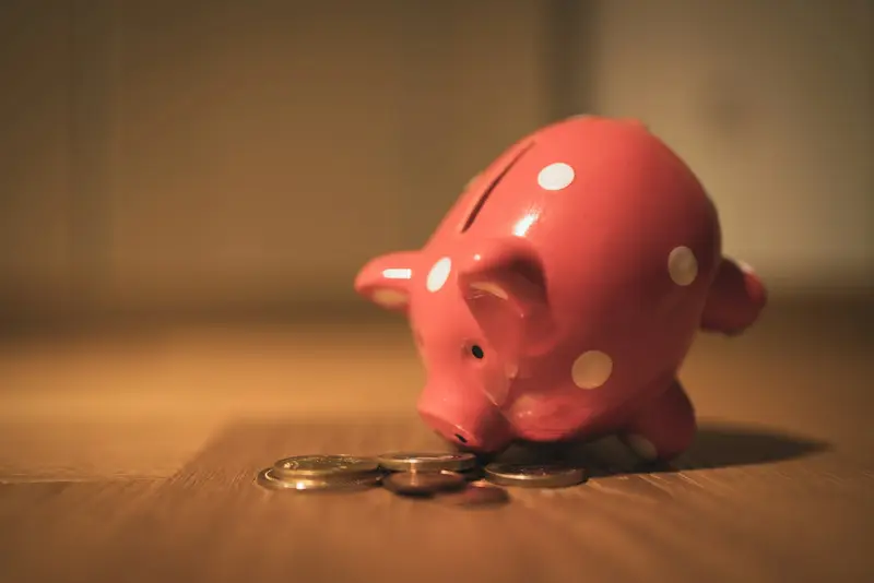 Pink piggy bank on a wooden table, representing saving money on college tuition