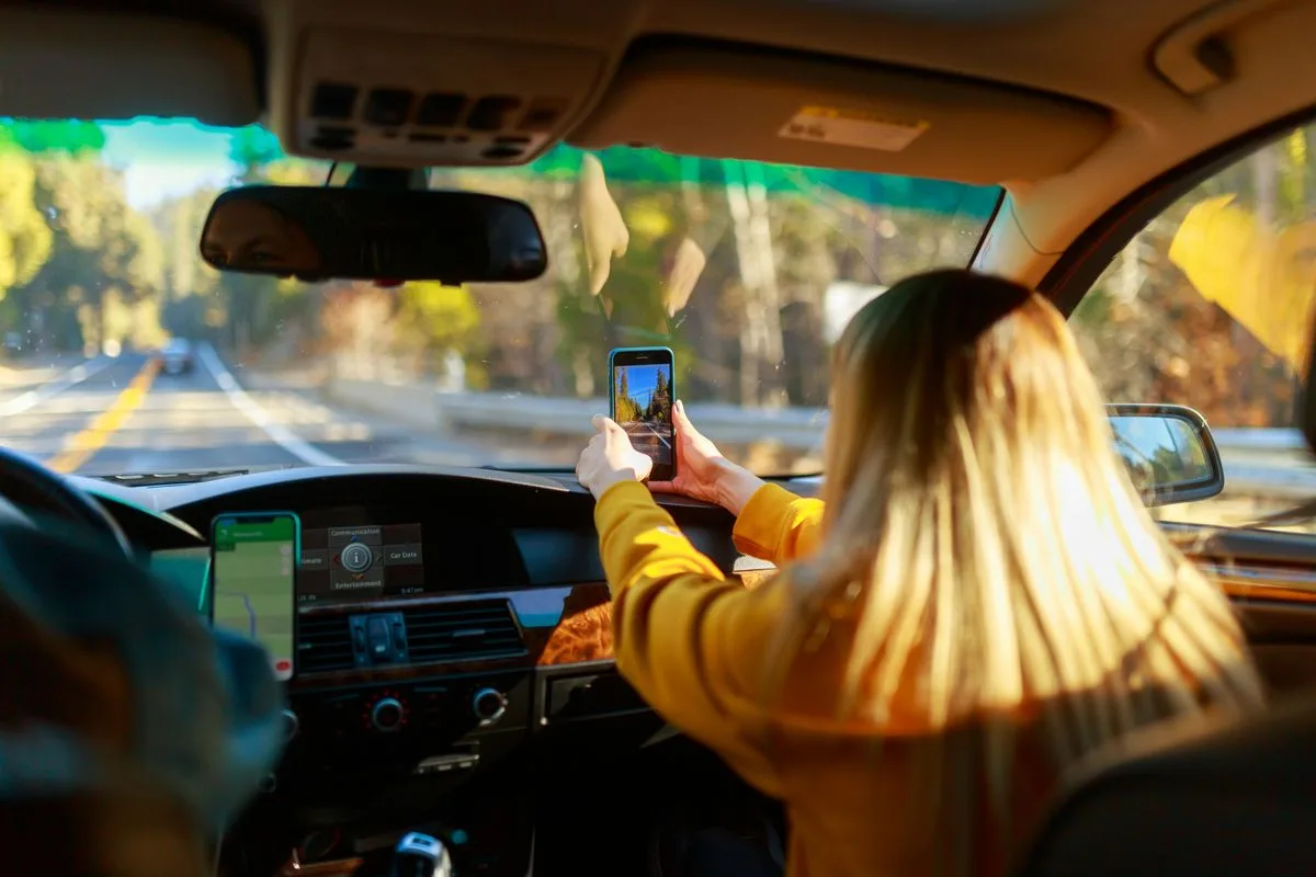 A woman driving a car on a road trip, planning a college campus visit