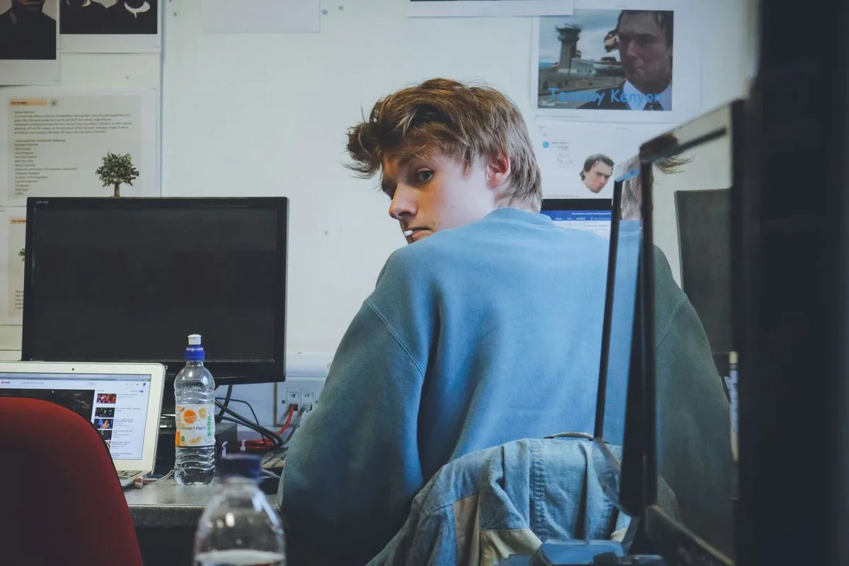 Man sitting in front of a computer screen, representing a student overwhelmed by the college search process