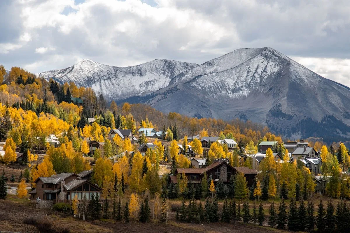 Aerial view of a small mountain town with forests and peaks in the background